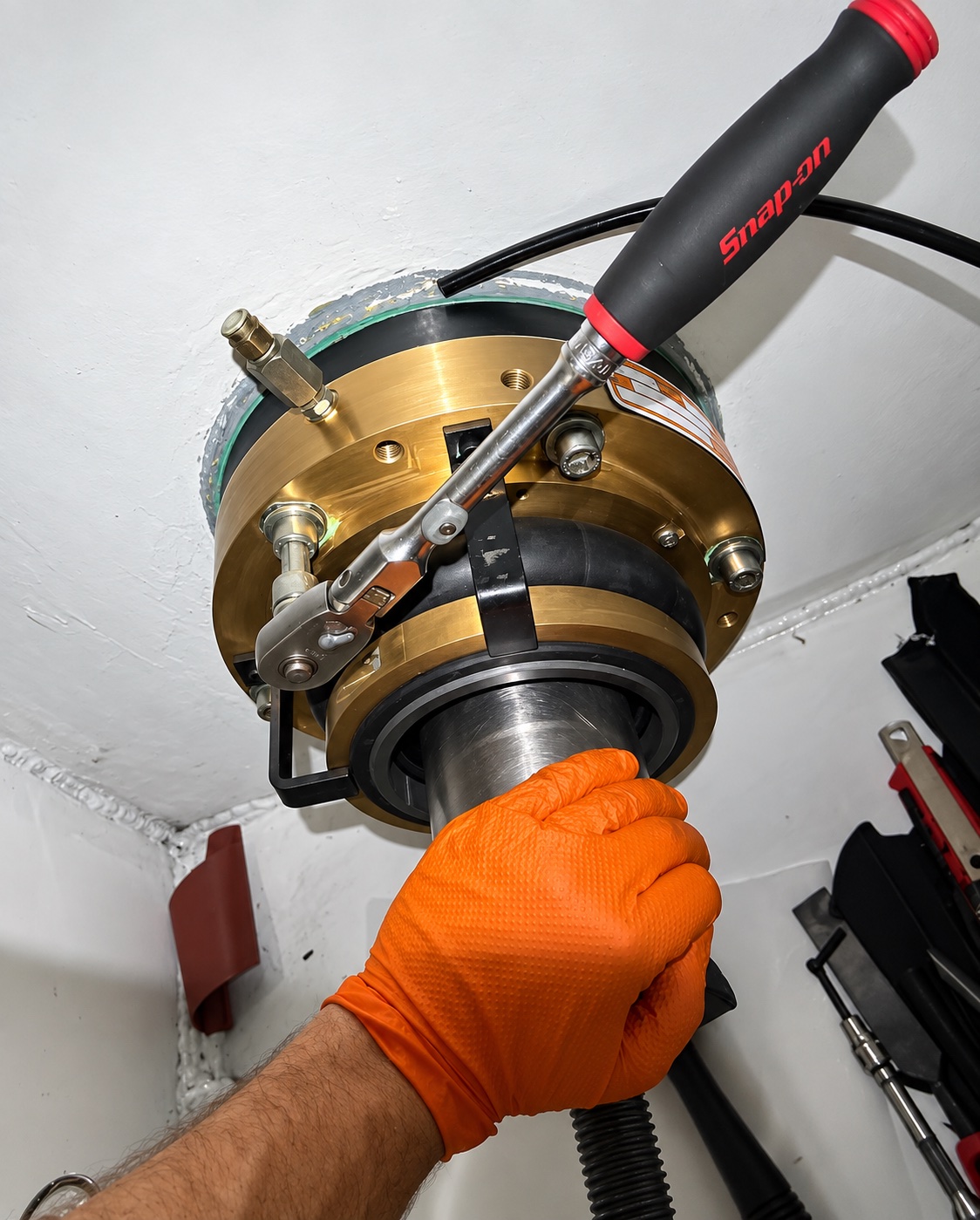 Gloved hand tightening a shaft seal with a ratchet